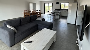 Ein modernes Wohnzimmer mit einer Eckcouch, einem Couchtisch und einem an der Wand befestigten Fernseher.