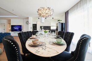 A modern dining area with a marble table, black upholstered chairs, and a unique chandelier.