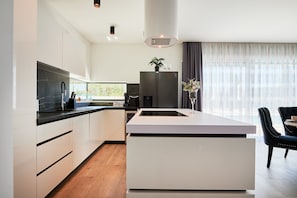 A modern kitchen with a central island, a built-in oven, and a refrigerator.