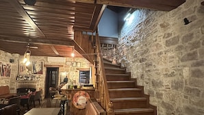 A restaurant interior with a wooden staircase, stone walls, and a bar area. - Alancha Otel (Ayvalik)