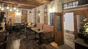 A rustic interior with wooden beams, stone walls, and a mix of seating areas including tables and benches. - Alancha Otel (Ayvalik)