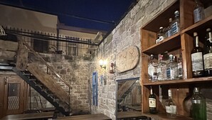 A rustic bar area with wooden furniture, stone walls, and a staircase. - Alancha Otel (Ayvalik)