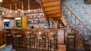A rustic bar area with wooden furniture, a stone wall, and a staircase. - Alancha Otel (Ayvalik)
