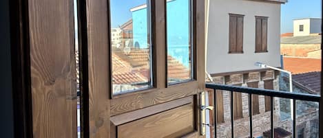 A wooden door with a view of a balcony and buildings in the background.