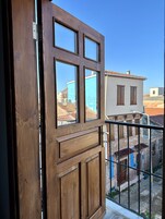 Una puerta de madera con vistas a un balcón y edificios al fondo.