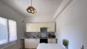 Eine moderne Küche mit weißen Schränken, einer weißen Arbeitsplatte und einem roten Tisch mit passenden Hocker.