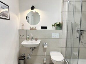 Un baño moderno con lavamanos, espejo, inodoro y ducha.