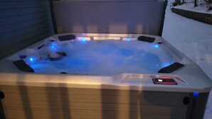 A hot tub with blue LED lights, surrounded by snow.