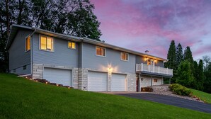 A two-story house with a garage, a balcony, and a well-maintained lawn.