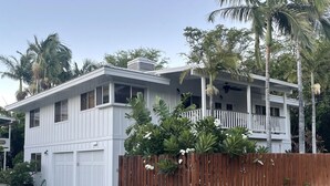 Ein zweistöckiges Haus mit weißer Fassade, einem Holzzaun und einer Veranda mit Geländer.