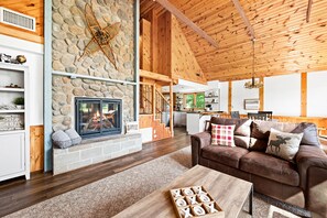 Cozy living area with a stone fireplace, comfortable sofa, and staircase leading to an upper level.