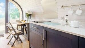 A modern kitchen with a large window, wooden cabinets, and a dining area with a chair.