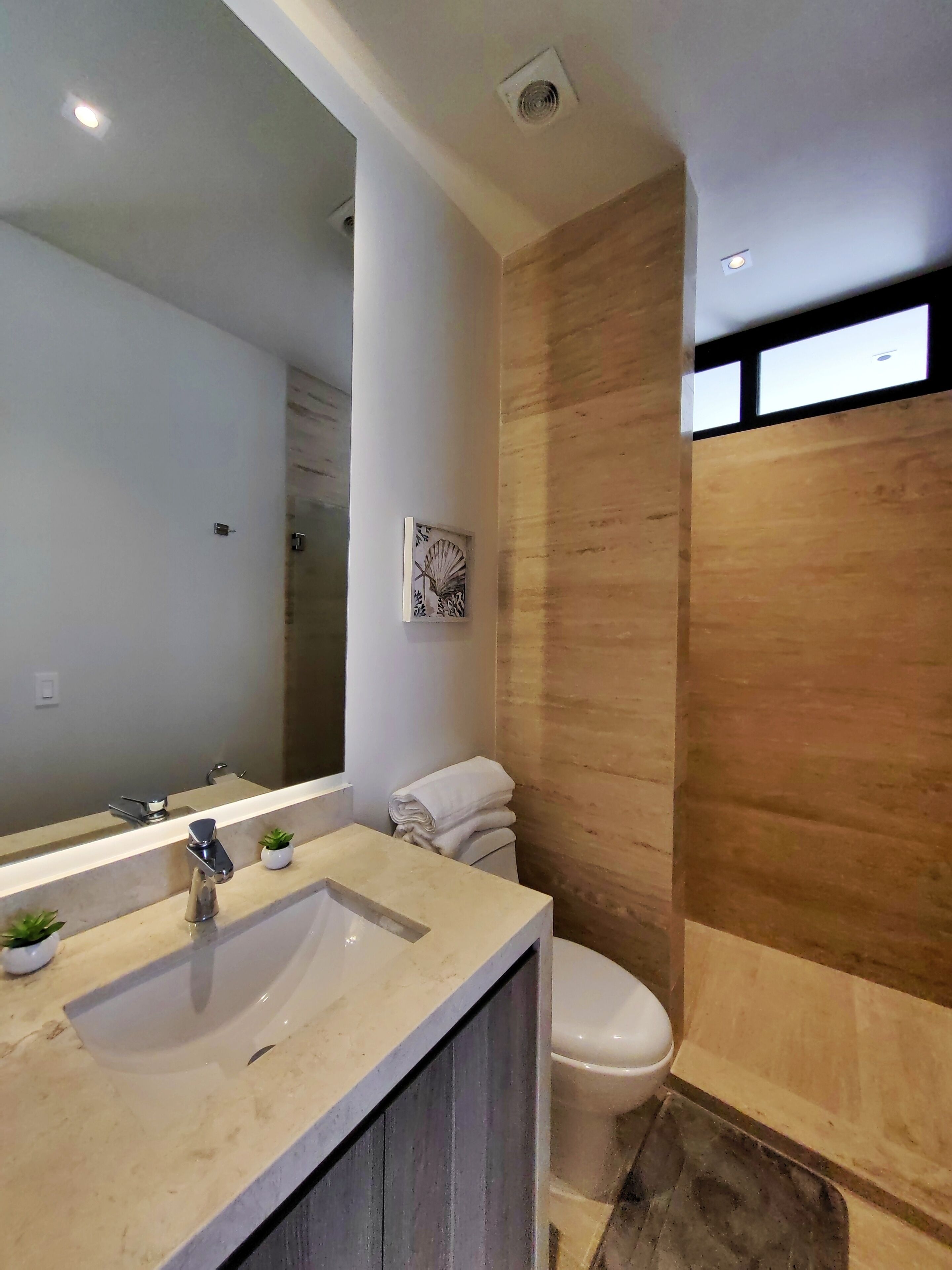Une salle de bain moderne avec un grand miroir, un lavabo et des toilettes.