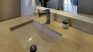 Une salle de bain moderne avec un grand lavabo, un miroir et une petite plante en pot.