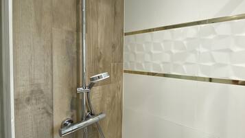 Une douche avec un mur en panneaux de bois et une partie recouverte de carreaux blancs.