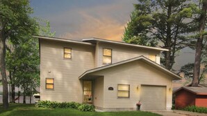 A two-story house with a garage, surrounded by trees and a well-maintained lawn. - East Twin Lake House - 2 Minutes to town (Lewiston)