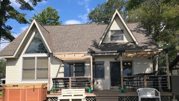 A two-story house with a covered porch, a hot tub, and a wooden deck. - East Twin Lake House - 2 Minutes to town (Lewiston)