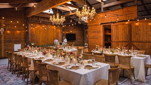 Een balzaal met lange tafels gedekt voor een formeel evenement, houten wanden, kroonluchters en een hoge plafond.