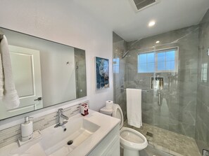 Une salle de bain moderne avec un grand miroir, un lavabo, des toilettes et une douche à parois de verre.