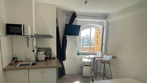 Una cocina compacta con microondas, pileta y un pequeño comedor con mesa y sillas.