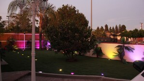 Un jardí ben cuidat amb un camí de maó, gespa i diferents arbres.