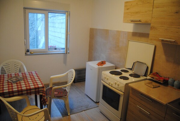 A compact kitchen with a stove, refrigerator, and a dining area with a table and chairs.