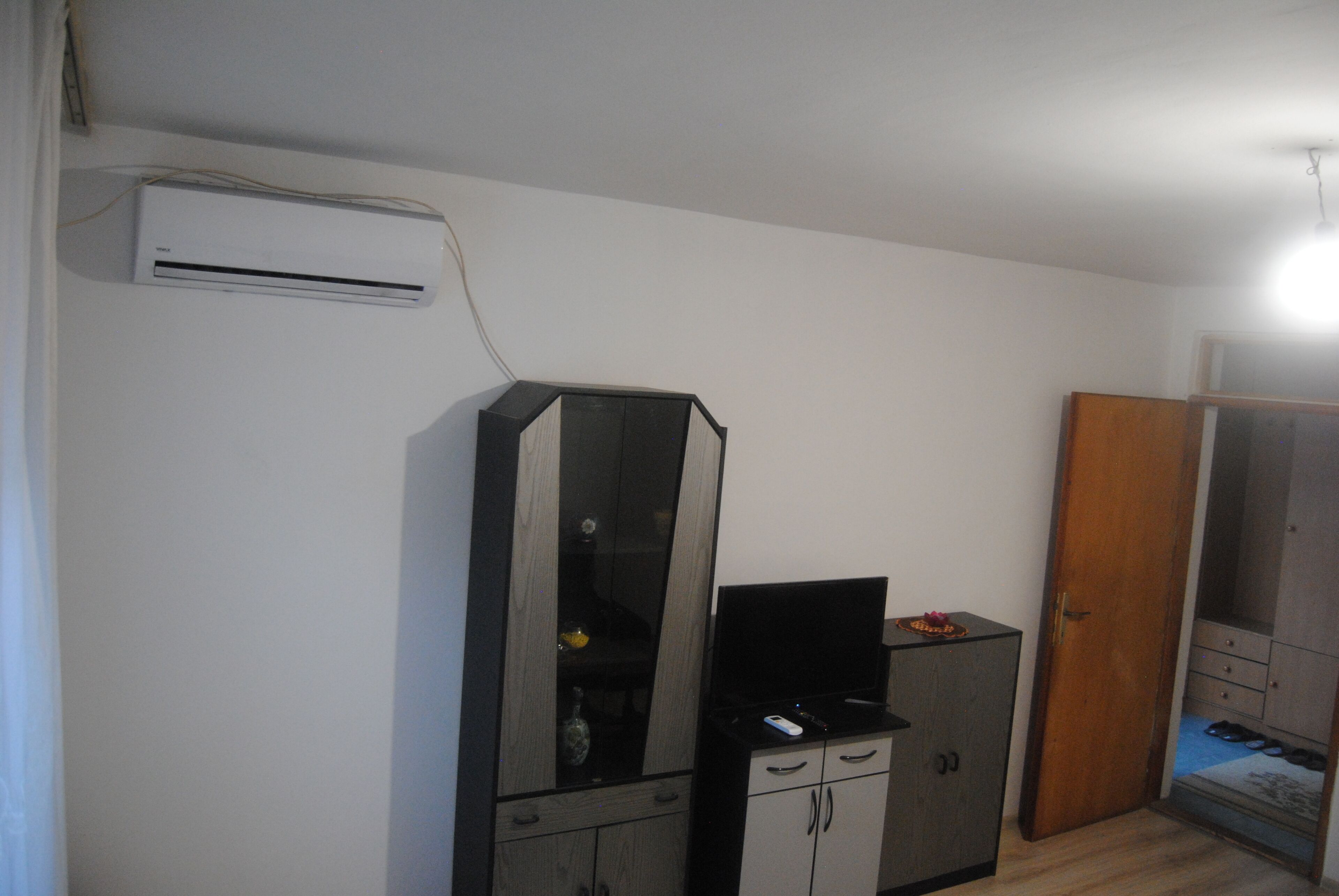 Ein Zimmer mit Schrank, Spiegel, Fernseher und Klimaanlage.