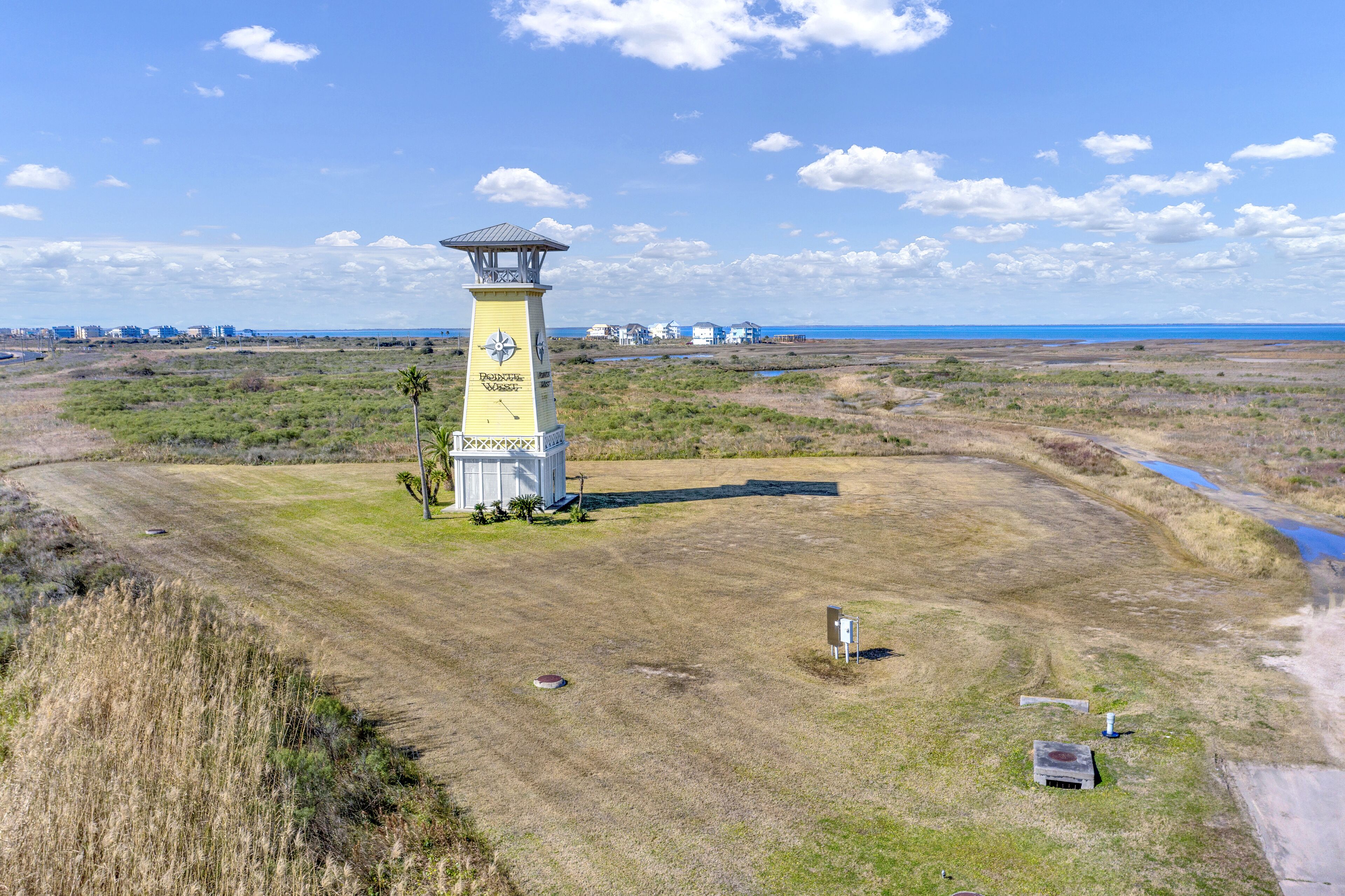A lighthouse with a clear view of the surrounding landscape, including distant buildings and a body of water.