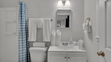 Een bad/douchecombinatie, handdoeken, zeep, toiletpapier