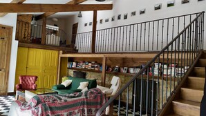 Une pièce spacieuse avec un plafond haut, un escalier et un balcon.