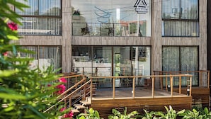 Um edifício moderno com deck de madeira, grandes janelas e um logotipo na fachada.