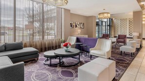 Un moderno vestíbulo de hotel con un sofá, sillones, una mesa de centro y una alfombra estampada.