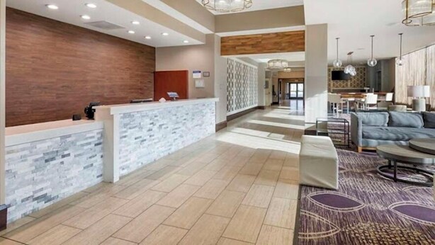 Un moderno vestíbulo de hotel con recepción, zona de estar y comedor.