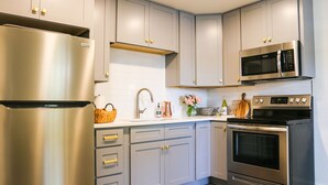 Een moderne keuken met roestvrijstalen apparatuur, grijze kastjes en een houten aanrechtblad.