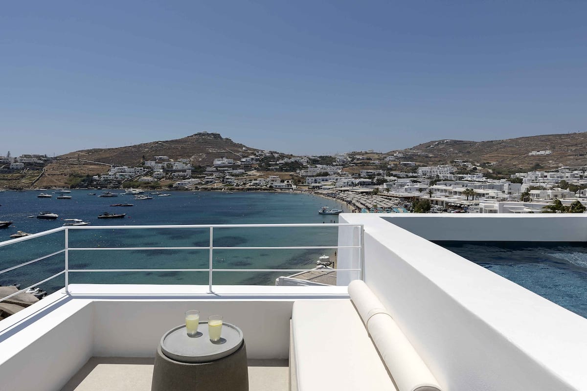 A balcony with a view of the sea, boats, and a coastal town.