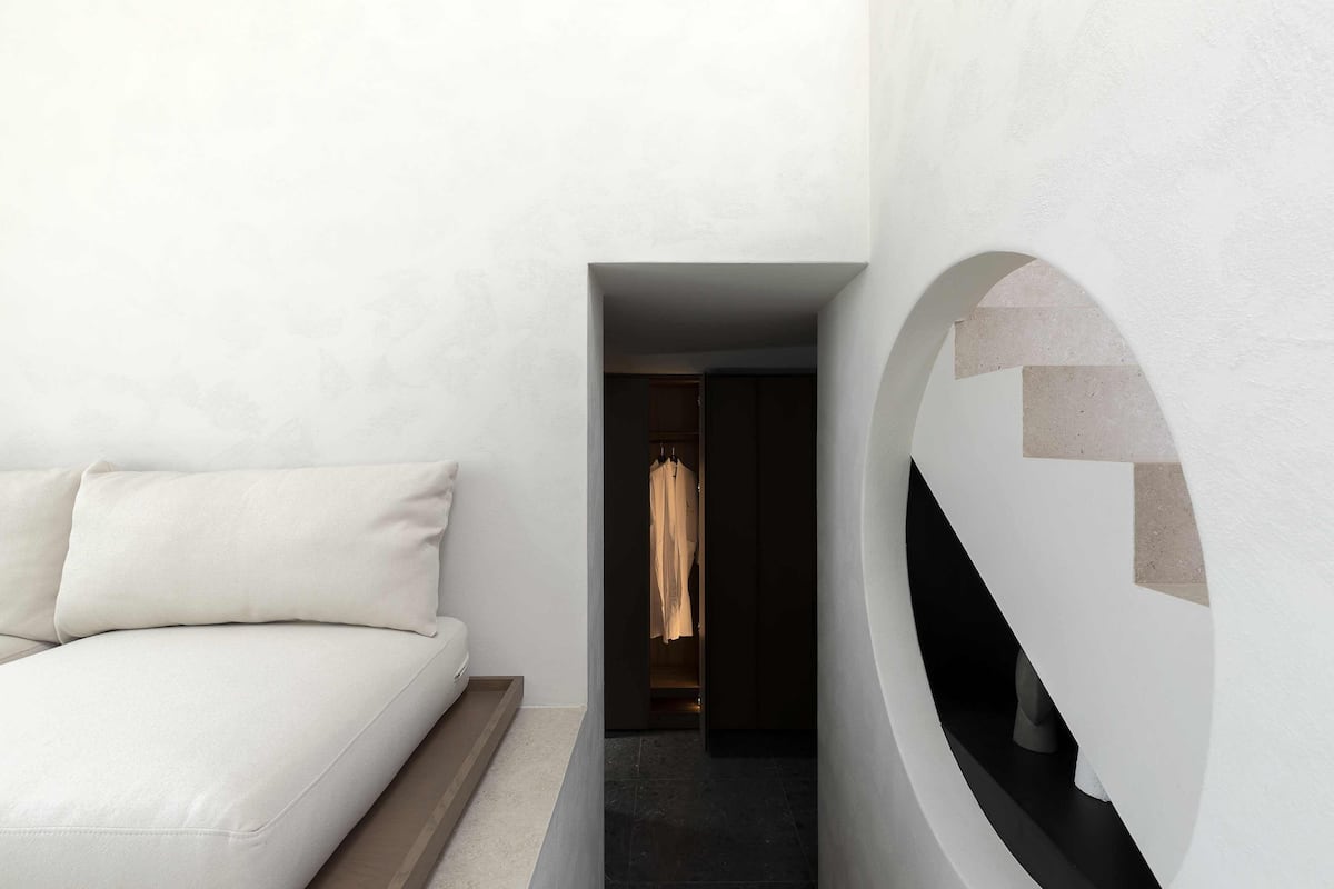A modern bedroom with a bed, a circular wall feature, and a hallway leading to a closet.