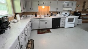 A kitchen with white cabinets, a stove, a dishwasher, and a coffee maker.