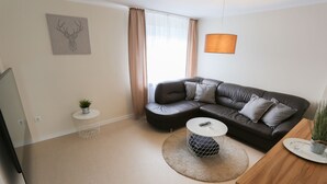 A modern living room with a sectional sofa, a round coffee table, and a TV. - Moderne Ferienwohnung in Kassel (Kassel)