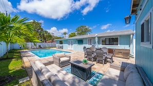 A backyard with a swimming pool, outdoor furniture, and a barbecue area.