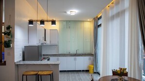A modern kitchen with white cabinets, a granite countertop, and a small island with stools.