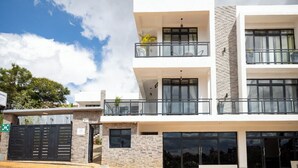 A modern multi-story building with balconies, large windows, and a stone facade.