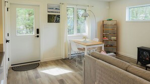 Una sala de estar moderna con un sofá, una mesa de comedor con sillas, una estantería y una chimenea.