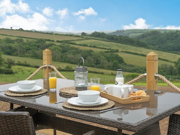 Una mesa al aire libre con desayuno y una vista panorámica de colinas ondulantes.