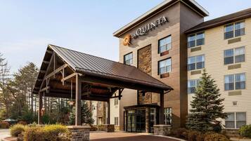 A hotel with a covered entrance, a stone facade, and a sign reading "LA QUINTA".