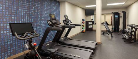 A gym with treadmills, a stationary bike, and weightlifting equipment.