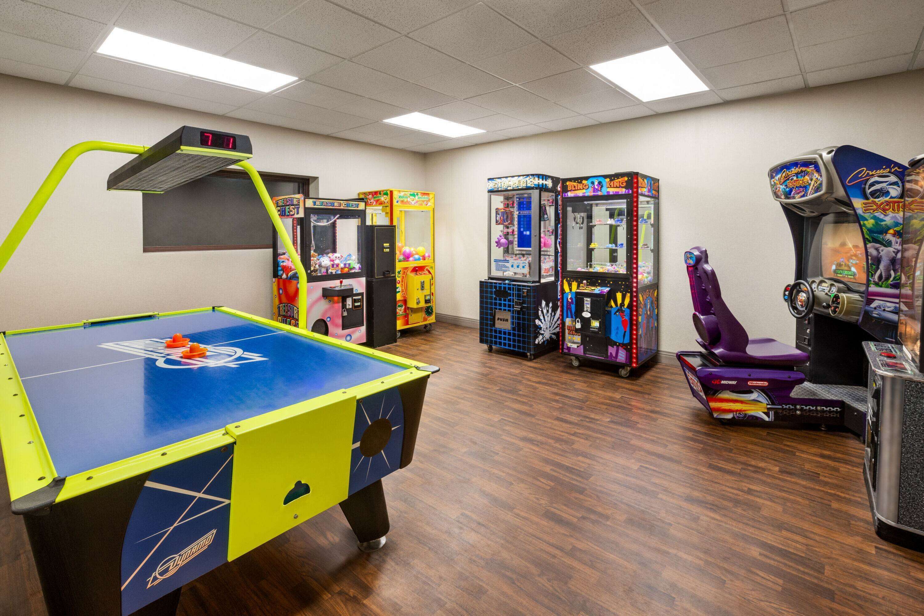 A room with a pool table, arcade games, and a claw machine.