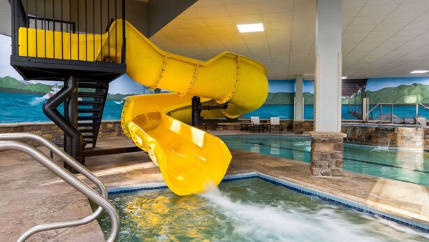 Un área de piscina con un tobogán de agua amarillo y una piscina.