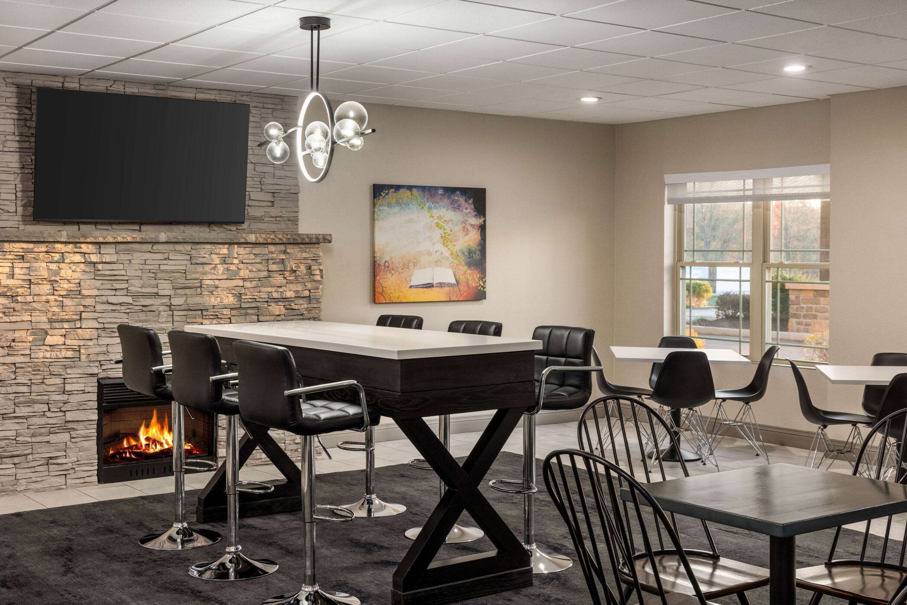 A conference room with a stone fireplace, a large table, and black chairs.