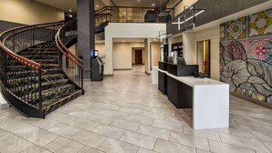 Un vestíbulo espacioso con una escalera curva, un mostrador de recepción y un muro decorativo.
