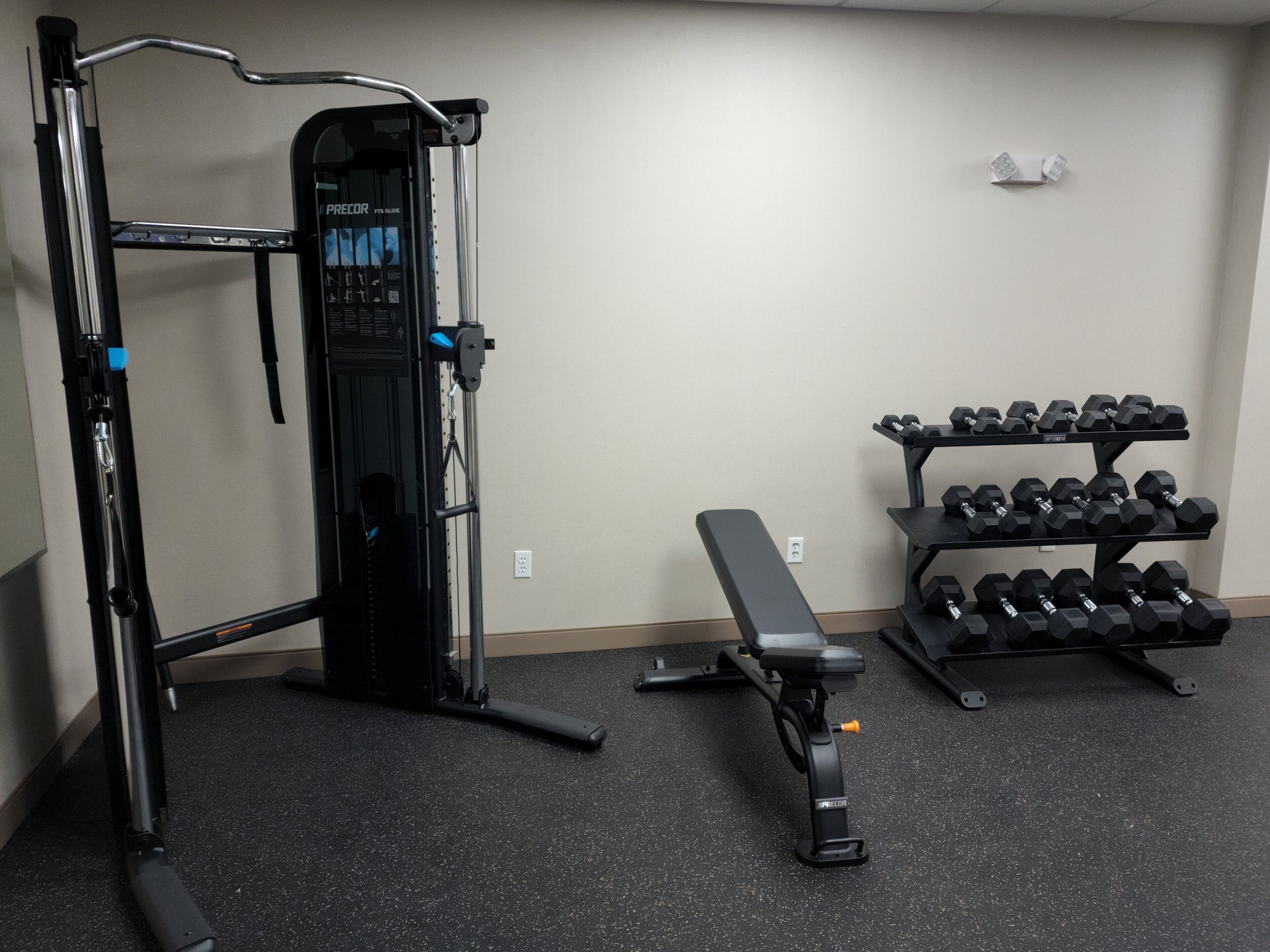 A gym with a squat rack, bench, and dumbbells.